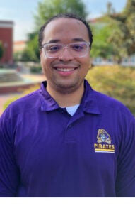 Man in purple shirt wearing glasses.